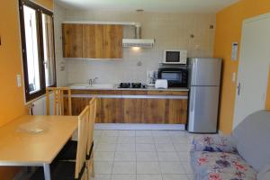 a small kitchen with a refrigerator and a table and a couch at Gîte 1805 Montagnes du Jura avec Spa et Sauna classé 2 étoiles in Foncine-le-Haut