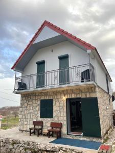 a house with two benches in front of it at Guest House Markovic Lovcen in Cetinje