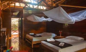 a bedroom with two beds and a net at Tambopata Edosikiana Lodge in Tambopata