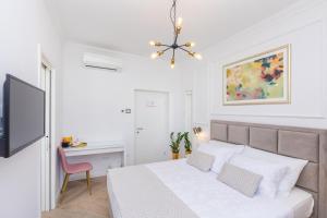 a white bedroom with a bed and a desk at Rooms D&L, FREE Parking on-site in Dubrovnik