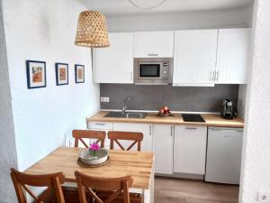 a kitchen with white cabinets and a wooden table at Apartament Port de la Selva in Port de la Selva