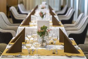 długi stół z kieliszkami do wina i kwiatami na nim w obiekcie Willis Hotel Business & Wellness w mieście Zalaegerszeg