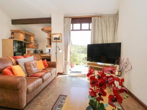 a living room with a brown couch and a television at Topiary Cottage in Staveley