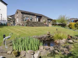 a garden with a pond in front of a house at Topiary Cottage in Staveley