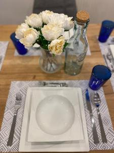 uma mesa com um prato e um vaso de flores brancas em #lowcosthighcomfort em Leoben