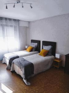 a bedroom with two beds with yellow pillows at Paisible studio avec agréable loggia 2 mn du centre in Aix-les-Bains