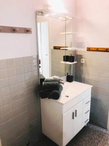 y baño con lavabo blanco y espejo. en Paisible studio avec agréable loggia 2 mn du centre, en Aix-les-Bains