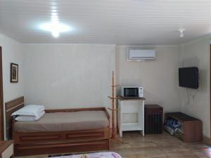 une petite chambre avec un lit et une télévision dans l'établissement V do Lago Negro, à Gramado