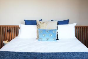 a bed with white sheets and blue pillows at Picobello Lago in Mandello del Lario
