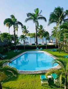 een groot zwembad met palmbomen en de oceaan bij La Dolce Vita Beachfront Apt 2 in Las Terrenas