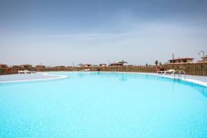 una gran piscina azul con 2 sillas blancas en Villa Sofía Fuerteventura, en Lajares