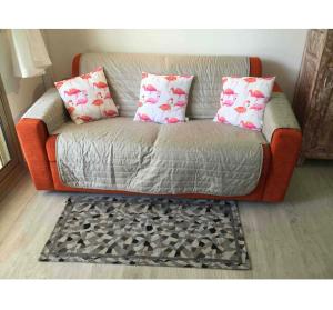- un canapé orange avec deux oreillers et un tapis dans l'établissement T2 A/C côte d'Azur, piscine, plage á 350m, WIFI, à Vallauris
