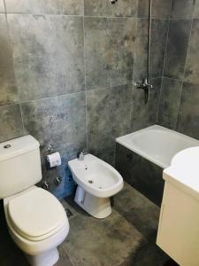 a bathroom with a toilet and a sink and a tub at Balcones del boulevard in Mariano J. Haedo