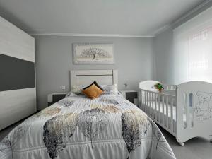 sypialnia z białym łóżkiem i łóżeczkiem dziecięcym w obiekcie Apartamentos María de Lucía-Piso 2º w mieście Arou