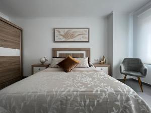 sypialnia z dużym łóżkiem i krzesłem w obiekcie Apartamentos María de Lucía-Piso 2º w mieście Arou
