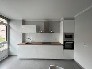 kuchnia z białymi szafkami, zlewem i oknem w obiekcie Apartamentos María de Lucía-Piso 2º w mieście Arou