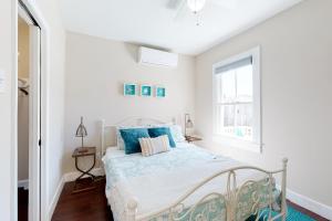a white bedroom with a bed with blue pillows at Market Gem in Galveston