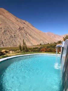 a pool of blue water with a waterfall at Cabañas Elquimista in Pisco Elqui