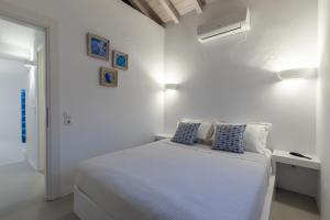 a white bedroom with a bed with blue pillows at Villa Mariel Skopelos in Skopelos Town