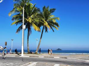 un grupo de personas caminando por una playa con palmeras en Jequiti-Mar Apto aconchegante na Enseada, en Guarujá