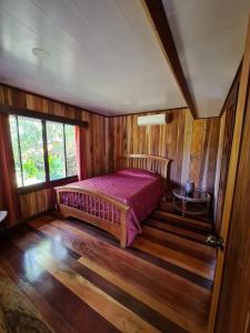 ein Schlafzimmer mit einem Bett in einem Zimmer mit Holzwänden in der Unterkunft Casa Numú in Cahuita