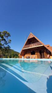 a resort with a swimming pool with a thatch roof at Hortênsias da Serra Pousada in Nova Friburgo +46 photos
