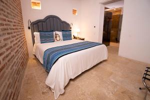 a bedroom with a large bed with blue pillows at Hotel Casa La Factoria by Faranda Boutique, a member of Radisson Individuals in Cartagena de Indias