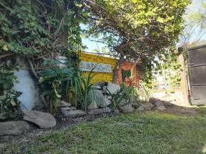 a garden with rocks and a building with a tree at Cabañas de Descanso Céntricas Cosquín in Cosquín