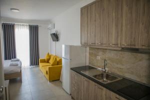 a kitchen with a sink and a refrigerator and a couch at Soluna Apartments in Shëngjin
