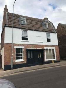 a white and red brick house on the side of a street at The Beehive, ground floor apartment in Norfolk, no shared amenities in Downham Market