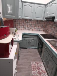 una piccola cucina con armadi bianchi e piastrelle rosse di Maison LUCIA a Saint-Pierre