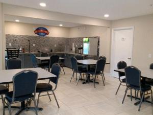 a dining room with tables and chairs and a kitchen at Baymont by Wyndham Lake Park Valdosta I75 in Lake Park