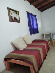 a bedroom with a bed with a blanket and a window at Cabaña Céntrica con Balcón Vista a las Sierras in Cosquín