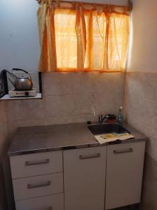 una pequeña cocina con fregadero y ventana en Cabaña Céntrica con Balcón Vista a las Sierras en Cosquín