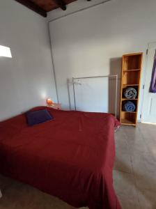 a bedroom with a red bed in a room at Cabaña Céntrica con Balcón Vista a las Sierras in Cosquín +8 photos