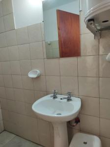 uma casa de banho com um lavatório, um WC e um espelho. em Cabaña Céntrica con Balcón Vista a las Sierras em Cosquín