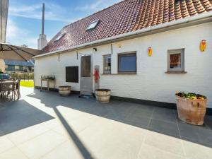un patio con una casa blanca con mesa y sillas en Beautiful Farmhouse in Beveren aan den IJzer with Terrace, en Beveren