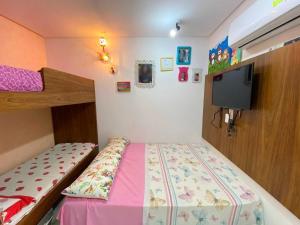 una piccola camera da letto con un letto e una TV di Monte Castelo Gravatá - Flat Aconchegante a Gravatá Altre 50 foto