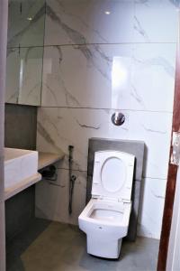 a bathroom with a white toilet and a marble wall at Hotel Park Side in Vasai