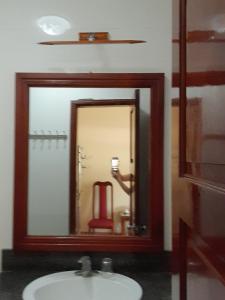 a bathroom mirror with a sink and a red chair at Khách sạn Vườn Quốc gia Ba Bể in Bak Kan