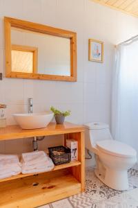 een badkamer met een wastafel, een toilet en een spiegel bij 360 Lodge Pichilemu in Pichilemu
