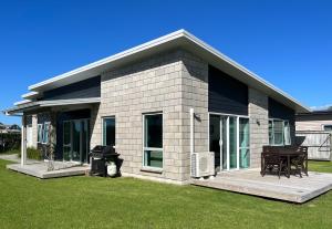 Cette petite maison dispose d'une terrasse couverte et d'un barbecue. dans l'établissement Surfers Retreat - Waihi Holiday Home, à Waihi Beach