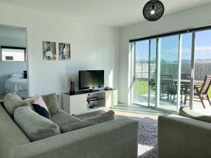 sala de estar con sofá y TV en Surfers Retreat - Waihi Holiday Home, en Waihi Beach