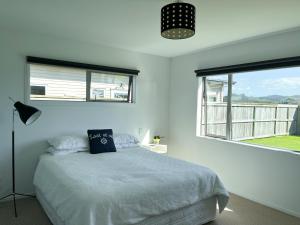 - une chambre blanche avec un lit et une fenêtre dans l'établissement Surfers Retreat - Waihi Holiday Home, à Waihi Beach