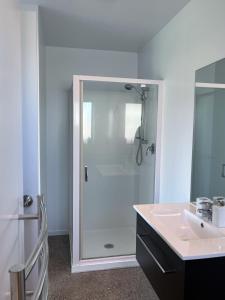 La salle de bains est pourvue d'une douche et d'un lavabo. dans l'établissement Surfers Retreat - Waihi Holiday Home, à Waihi Beach