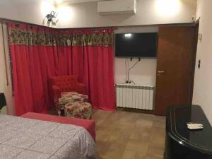 a bedroom with red curtains and a flat screen tv at Gran Casa Súper Equipada in Roldán