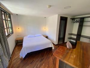 um quarto com uma cama branca e piso em madeira em Hostal Alcala em Quito
