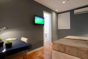 a bedroom with a bed and a desk and a tv on the wall at Bê Hotel in Sao Paulo