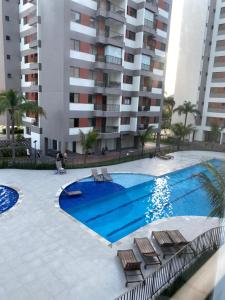 Una piscina con sillas y un edificio. en CARAGUA SOL E MAR, Piscina E lazer completo, en Caraguatatuba