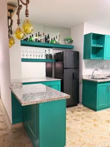 a kitchen with green cabinets and a black refrigerator at Hotel CastilloMar in Cartagena de Indias